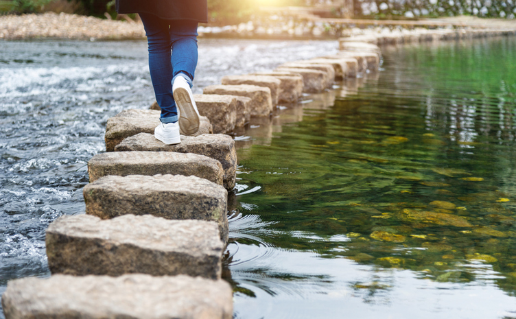 person walks over rocks in water